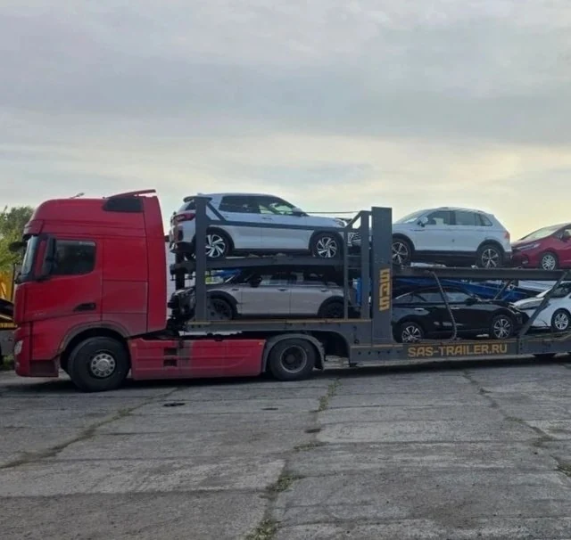 Красный автовоз с автомобилями во время перевозки